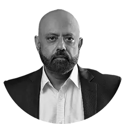 Manish Kanchan, Chairman and Chair of Investment Committee, wearing a formal suit and smiling warmly in a professional office setting with a calm and welcoming atmosphere